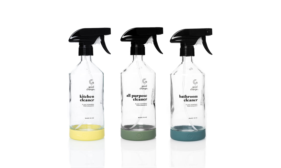 Three Good Change Bottle For Good glass spray bottles with sage green silicone sleeves on a kitchen bench.