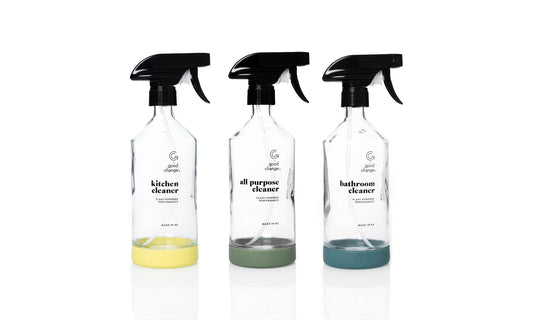 Three Good Change Bottle For Good glass spray bottles with sage green silicone sleeves on a kitchen bench.