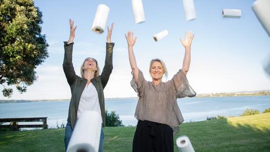Good Change co-founders Stine and Kristy throwing paper towel rolls into the air by the harbour