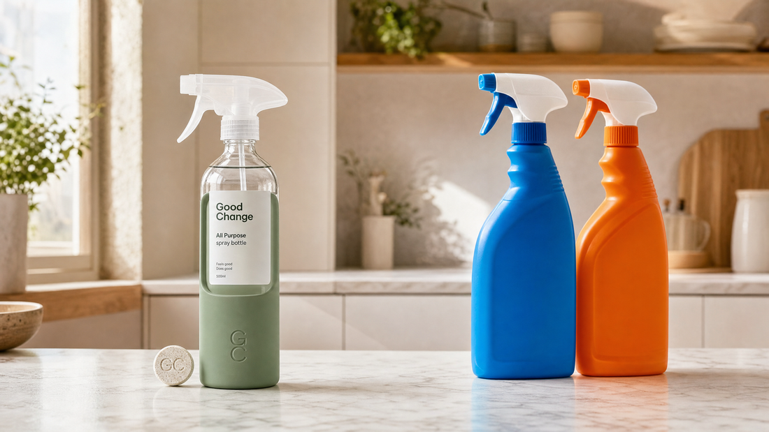 Good Change glass spray bottle with refill cleaning tablet next to supermarket plastic spray bottles on a marble kitchen counter