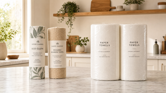Good Change Eco Cloth roll and Reusable Bamboo Towel roll next to two rolls of single-use paper towels on a marble kitchen counter